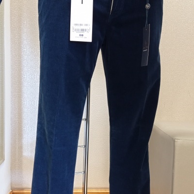 Calças azuis de veludo cotelê num manequim, com cinto castanho e casaco azul acolchoado