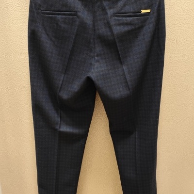 Calças azul escuro de padrão xadrez penduradas num cabide preto