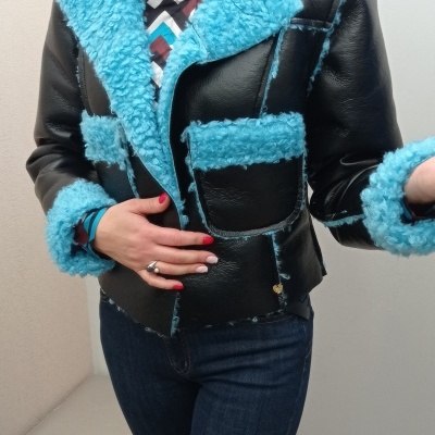 Casaco preto com pêlo azul turquesa e costuras azuis usado por mulher