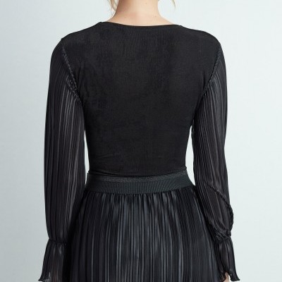 Vestido preto com mangas e saia plissadas visto de trás