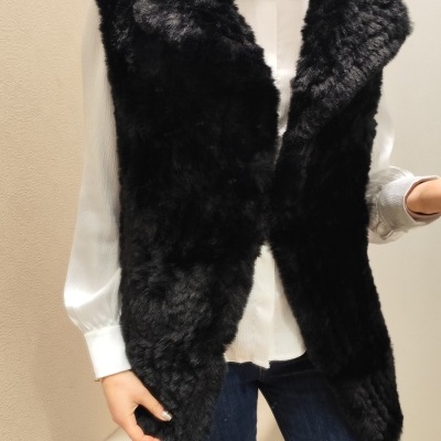 Colete de pelo preto macio sobre camisa branca e jeans azuis em interior