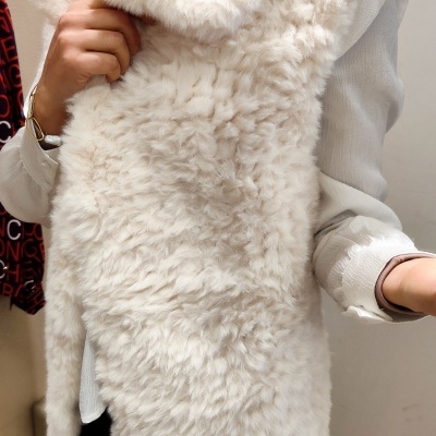 Colete de pelo sintético branco felpudo sobre camisa branca em ambiente interior