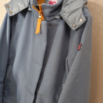 Casaco azul e cinza com fecho amarelo pendurado num cabide