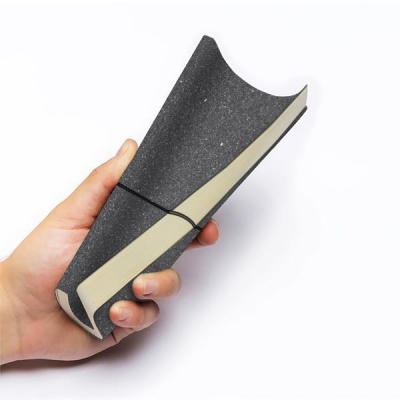 Peça curva acolchoada preta com faixa bege nas bordas na mão