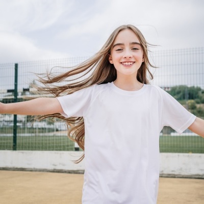 Camisola branca e calções vermelhos usados por criança sorridente ao ar livre