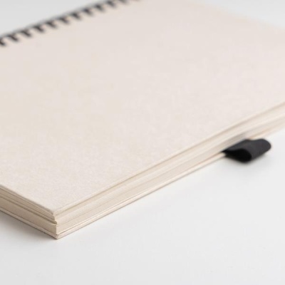 Caderno em espiral com capa dura bege sobre superfície branca