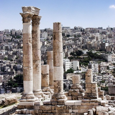 Ruínas antigas de colunas de pedra com cidade moderna ao fundo