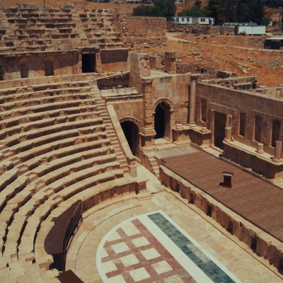 Anfiteatro romano antigo em pedra com assentos em meia-lua e plataforma central decorada