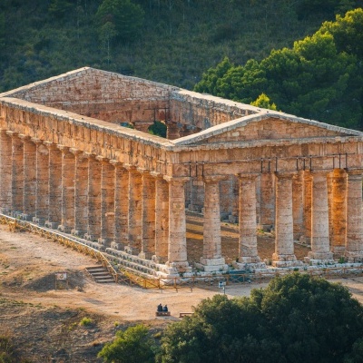 Templo antigo de pedra com colunas clássicas rodeado por vegetação