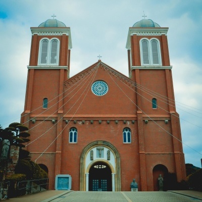 Fachada de igreja vermelha com duas torres e cúpulas verdes