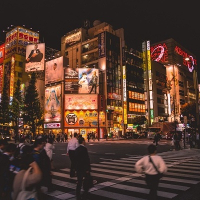 Cruzeiro urbano noturno com prédios iluminados e pessoas a atravessar a rua