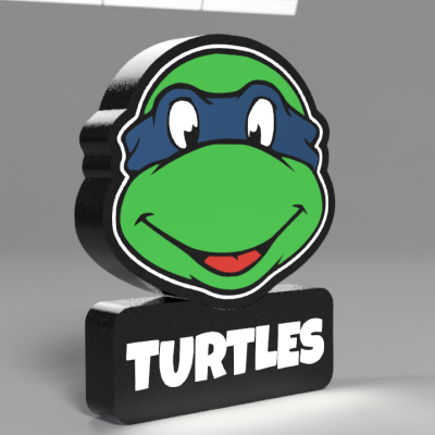 Figura decorativa cabeça de tartaruga verde com máscara azul e texto TURTLES em preto