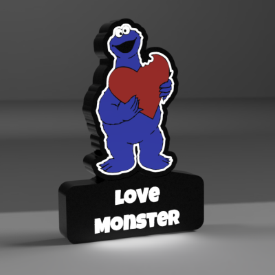 Figura decorativa com personagem azul a segurar coração e base preta com texto LOVE MONSTER.