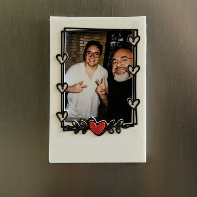 Fotografia em moldura branca com corações negros e um coração vermelho