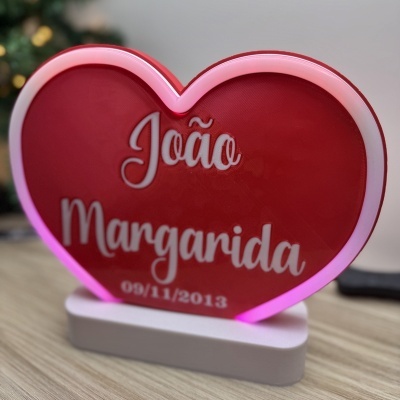 Objeto decorativo em forma de coração vermelho com texto branco e borda luminosa
