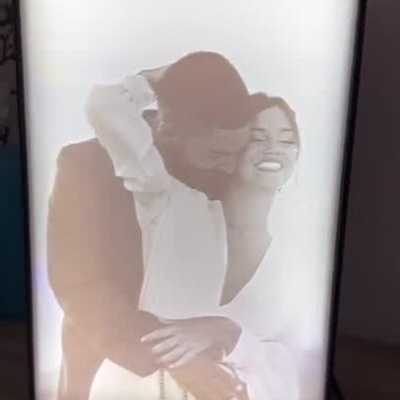 Moldura digital com foto em relevo que se ilumina mostrando um casal a abraçar