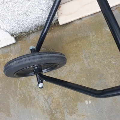 Roda preta de borracha e estrutura metálica sobre chão de cimento