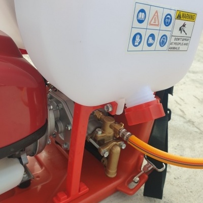 Pulverizador agrícola branco e vermelho com mangueira laranja e etiqueta de aviso