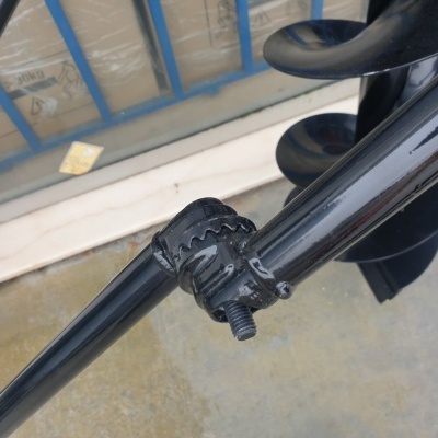 Suporte metálico preto com parafuso e hélice preta junto a janela com grades azuis