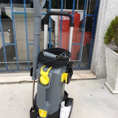 Máquina de limpeza a pressão cinza com detalhes amarelos e manguera enrolada