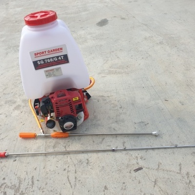 Pulverizador motorizado branco e vermelho com hastes metálicas num chão de cimento