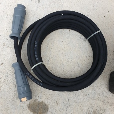 Cabo preto de borracha com conectores cinzentos sobre chão de cimento