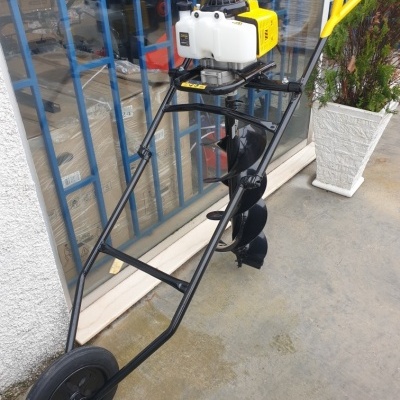 Perfuração de solo com motor e estrutura preta com alças amarelas