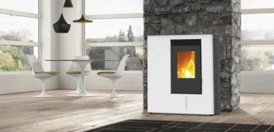 Lareira a pellets branca com moldura preta e chama visível, junto a parede de pedra, em sala com chão de madeira e mobiliário branco.