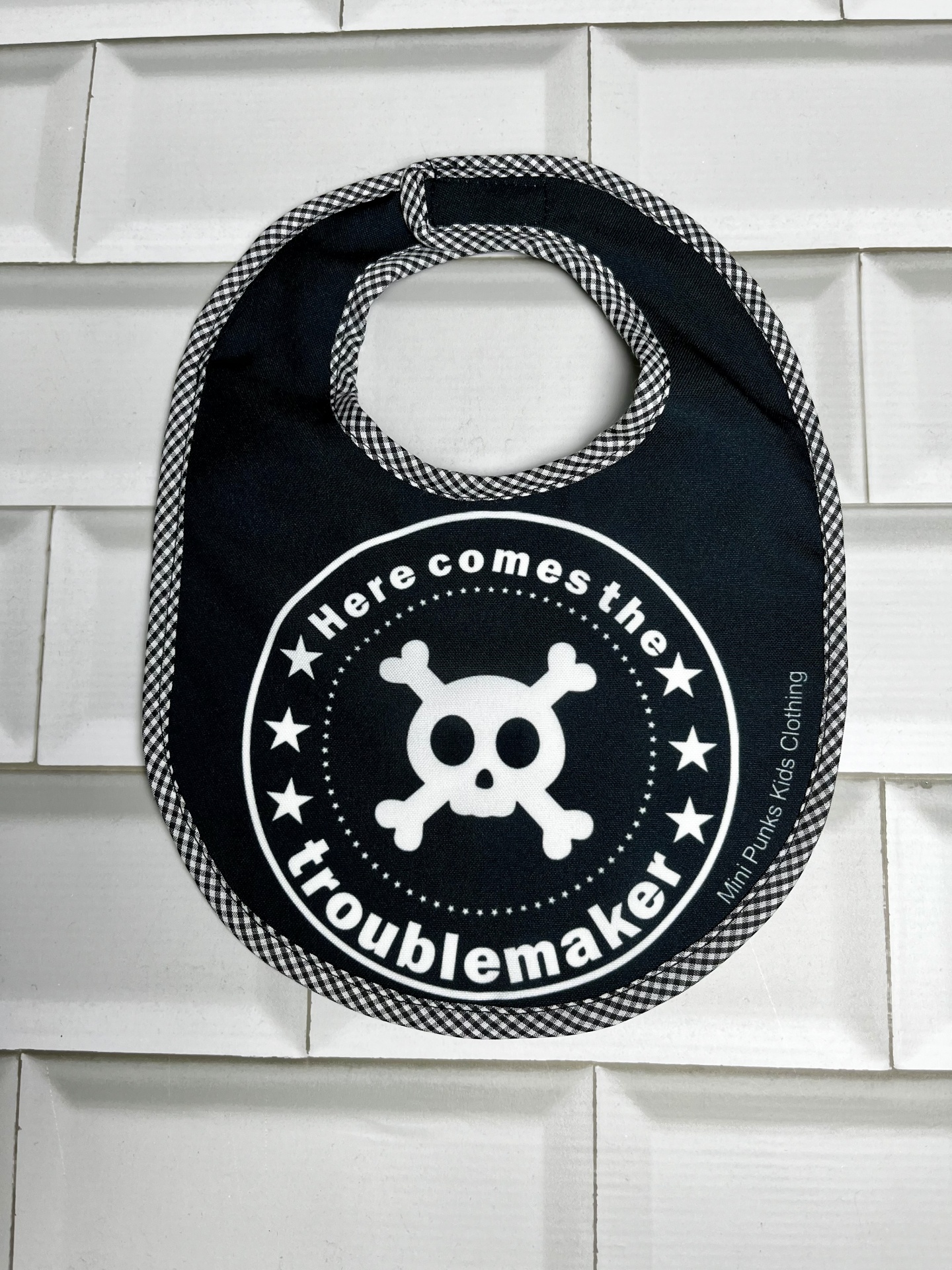 Babete preto com padrão xadrez e estampado de crânio com texto