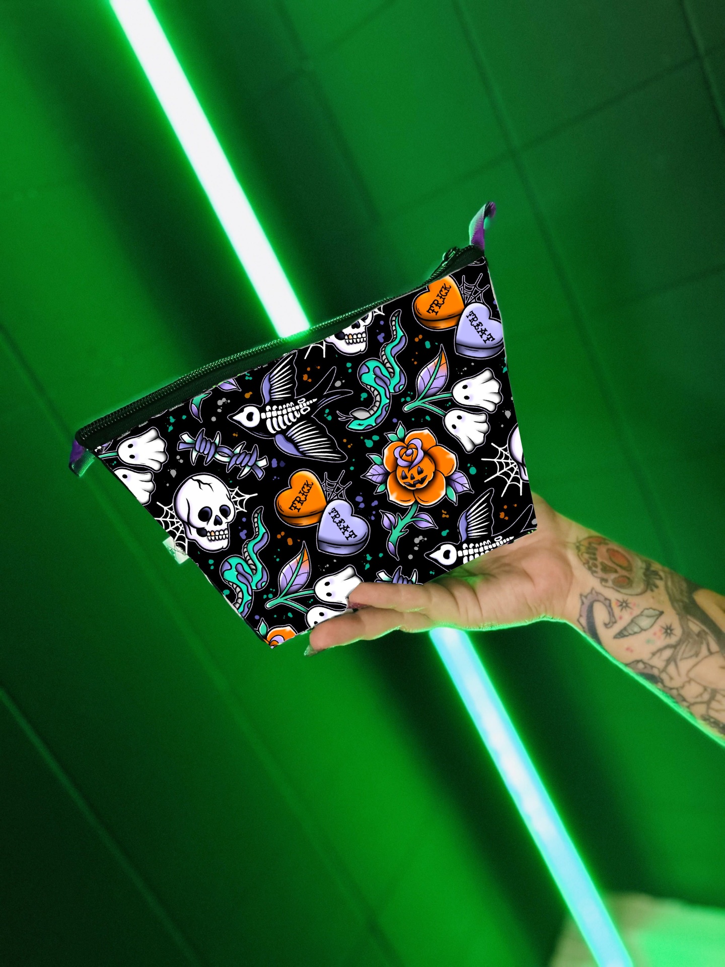 Bolsa preta com padrão de caveiras e desenhos coloridos segurada por mão tatuada