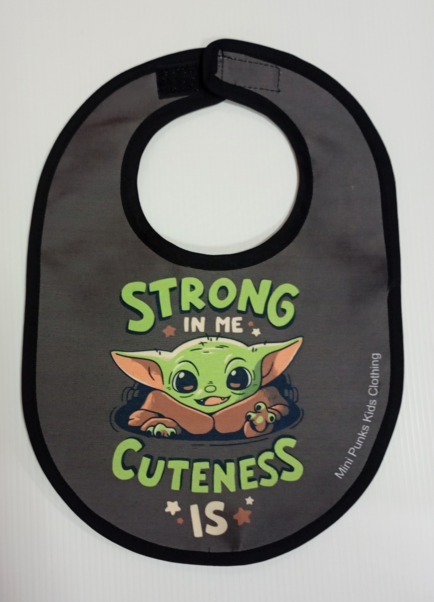 Babete cinzento escuro com bordos pretos e imagem colorida de personagem verde com texto