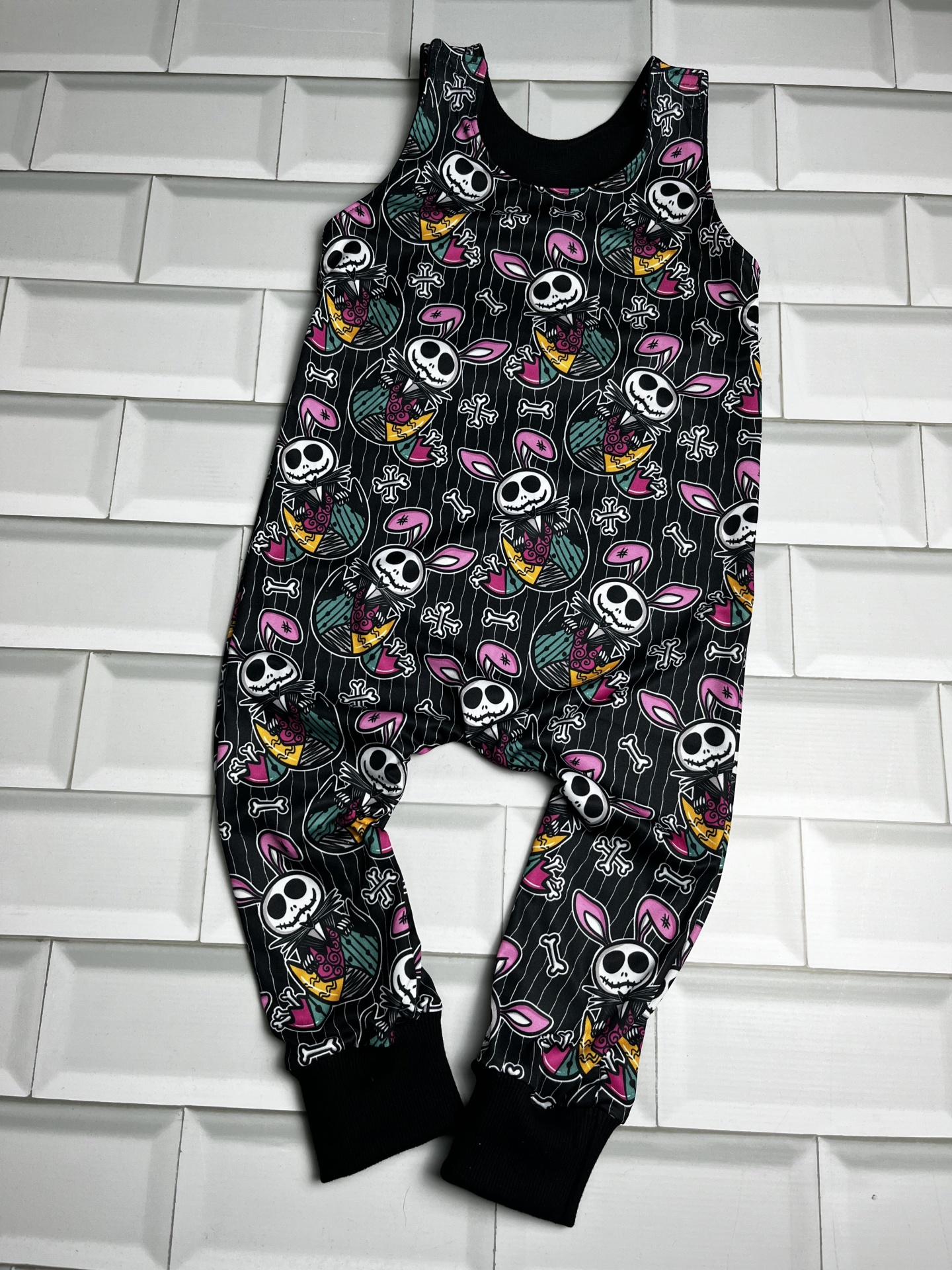 Macacão de criança com padrão de caveiras e orelhas de coelho cor-de-rosa