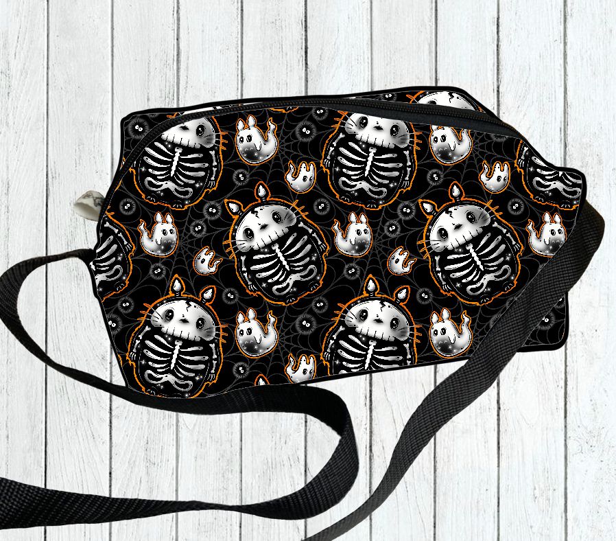 Mala tiracolo preta com padrão de esqueletos e laranja