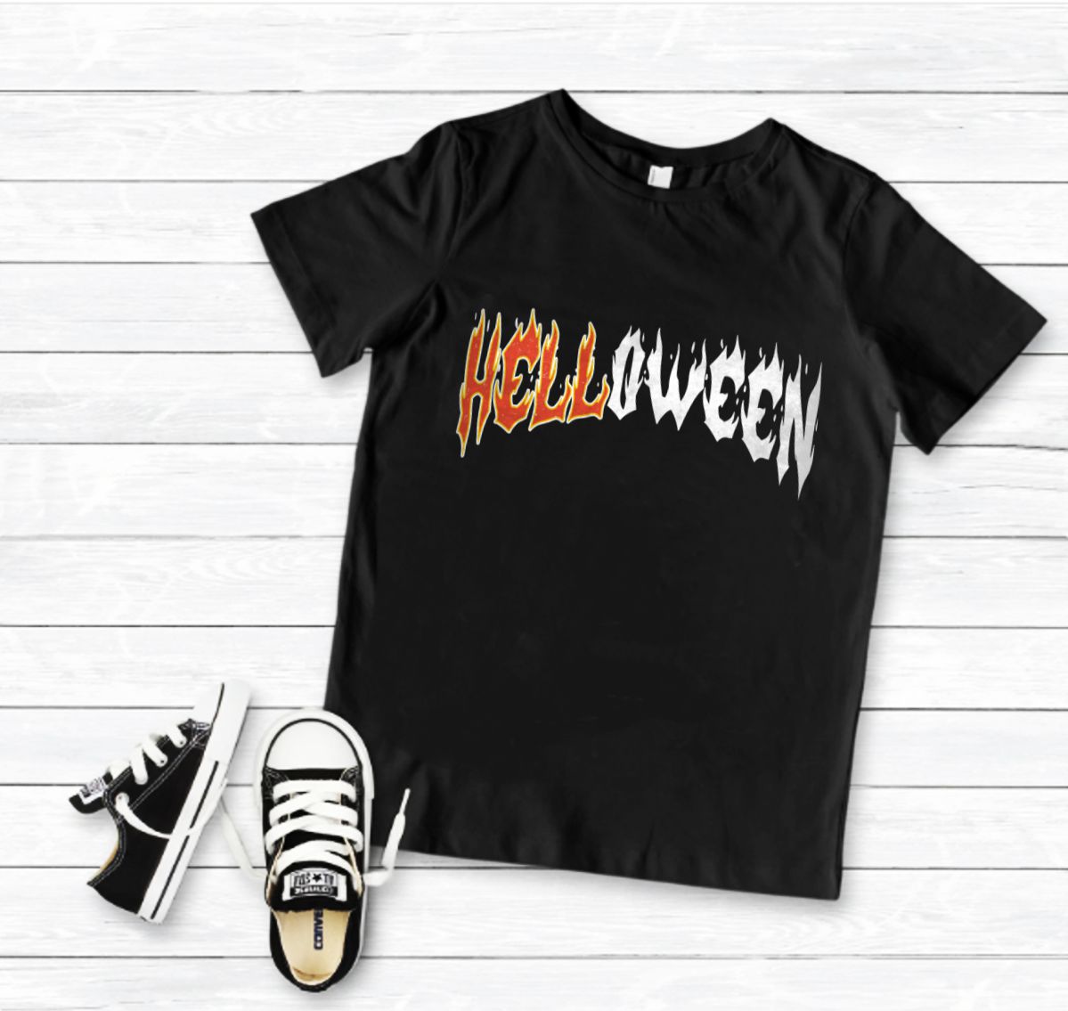 T-shirt preta com texto Halloween e sapatilhas negras sobre fundo de madeira clara.