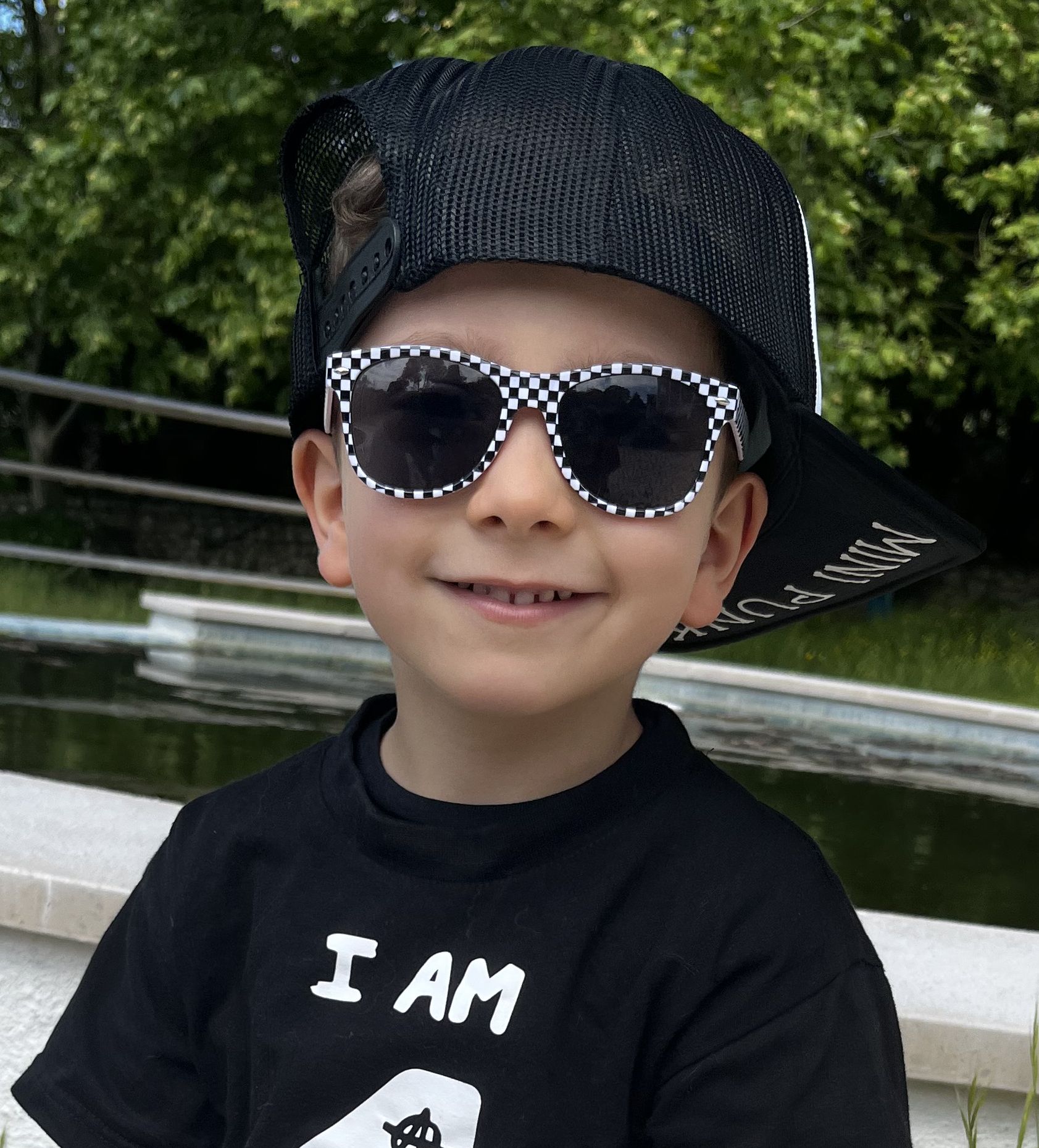 Criança com boné preto e óculos de sol xadrez