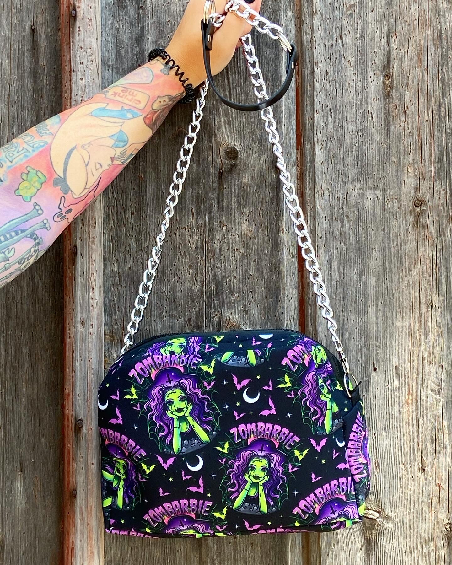 Mala preta com padrão de zumbis coloridos e alça de corrente prateada