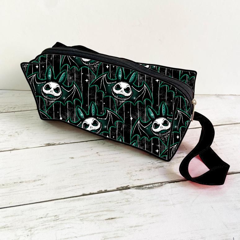 Carteira preta com padrão de caveiras e alça preta colocada em superfície de madeira clara