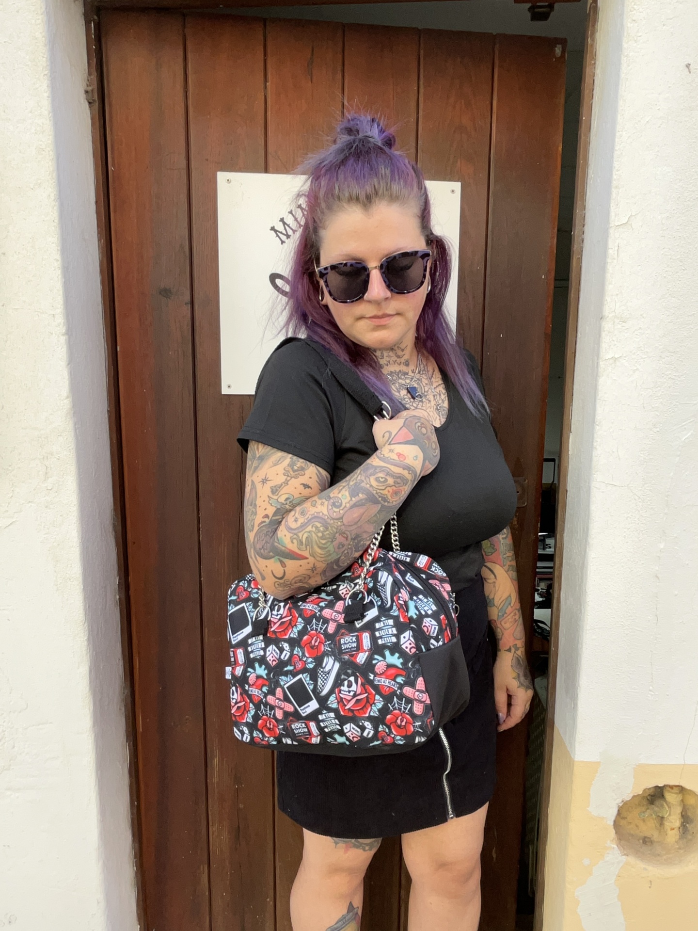 Mulher com mala preta estampada em frente a porta de madeira