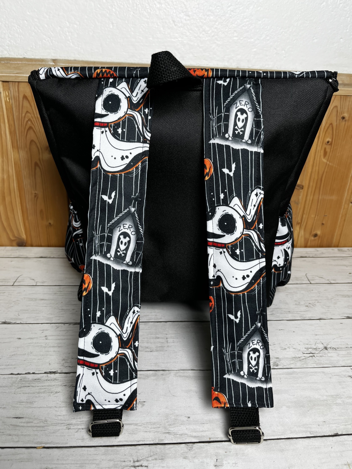 Mochila preta com alças estampadas com desenho de cão branco e elementos de Halloween