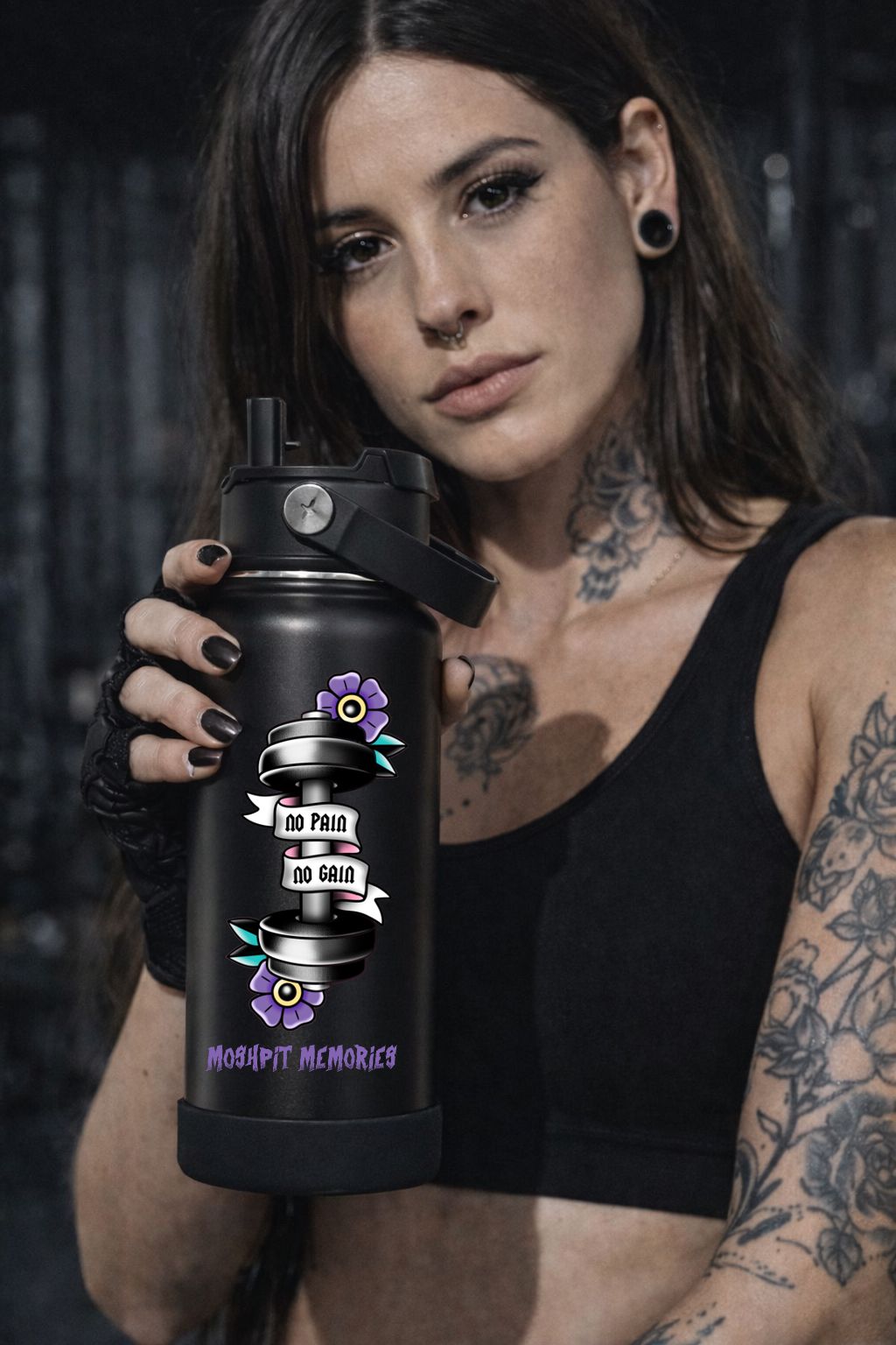 Garrafa desportiva preta com ilustração de halteres e flores e texto motivacional, segurada por mulher tatuada e vestida de preto.