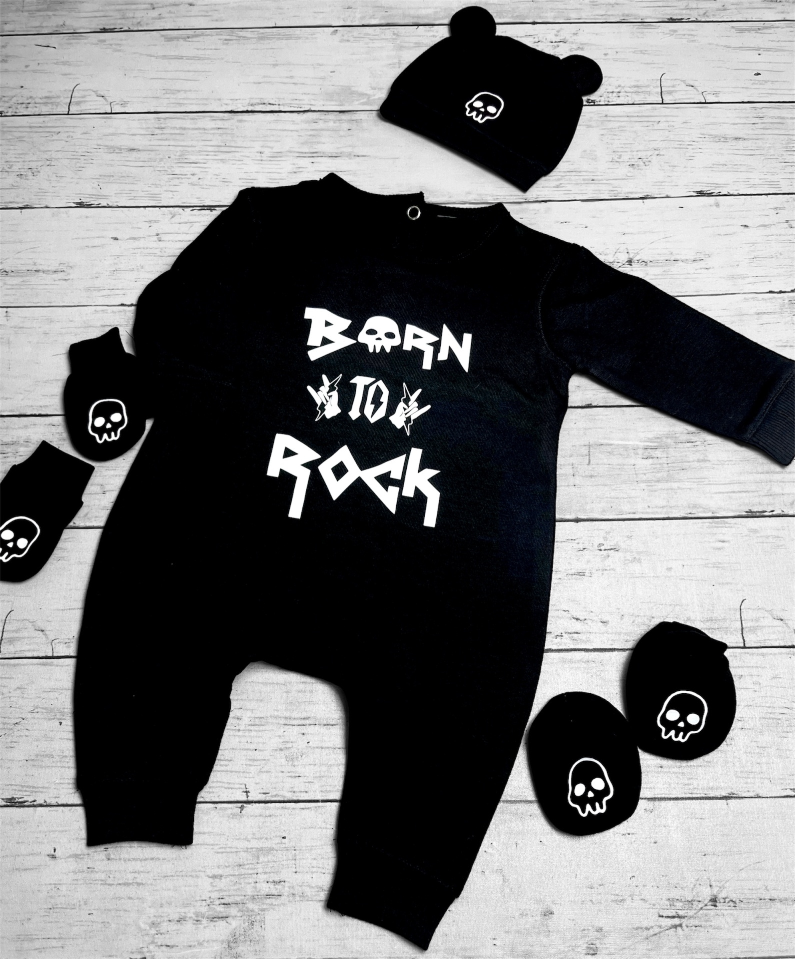 Conjunto de roupa de bebé preto com caveira branca e texto BORN TO ROCK