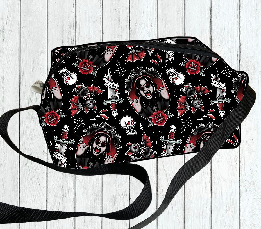 Bolsa preta com padrão de caveiras, rosas vermelhas, facas e rostos gritando