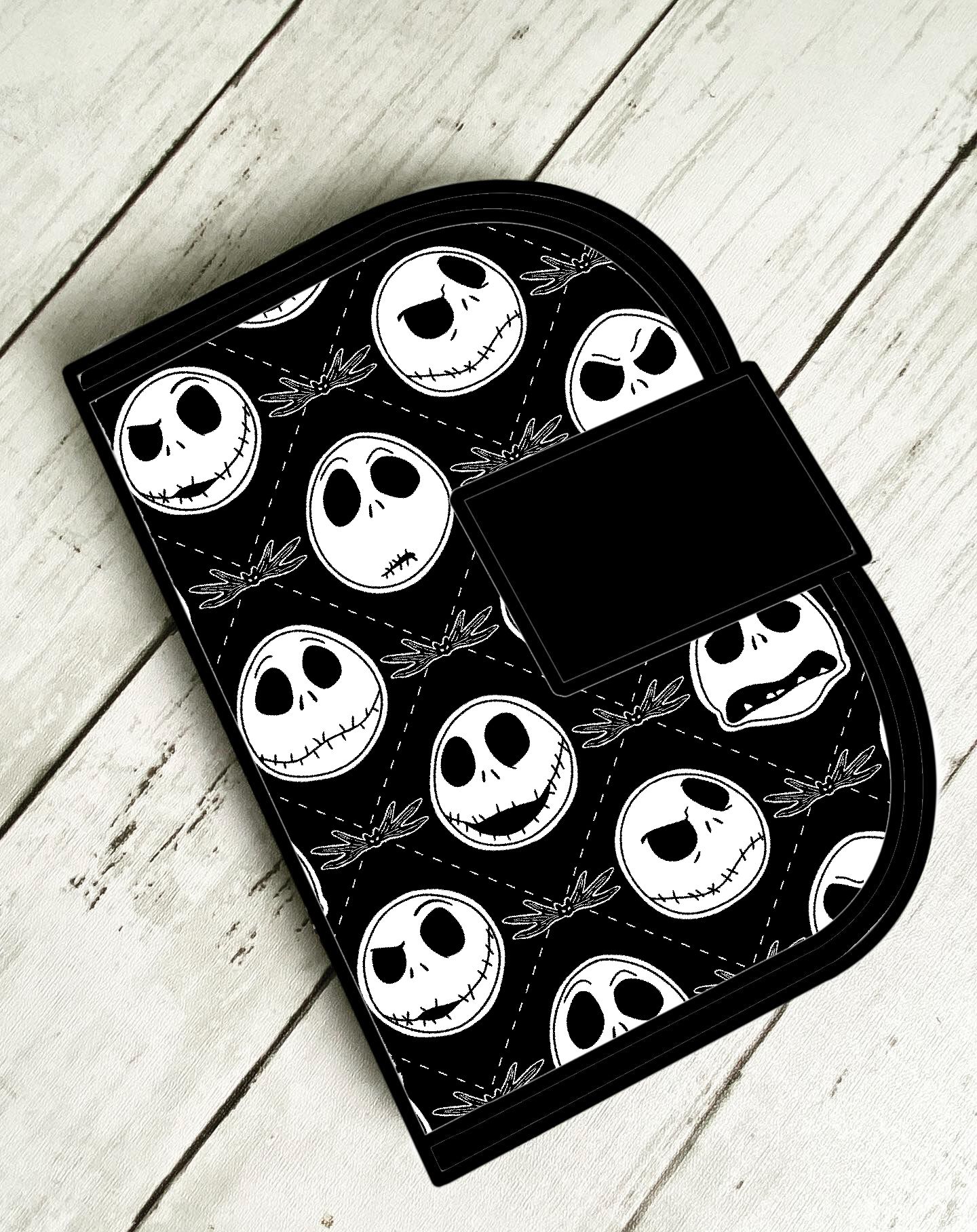 Bolsa preta com desenhos de caveiras brancas sobre madeira clara