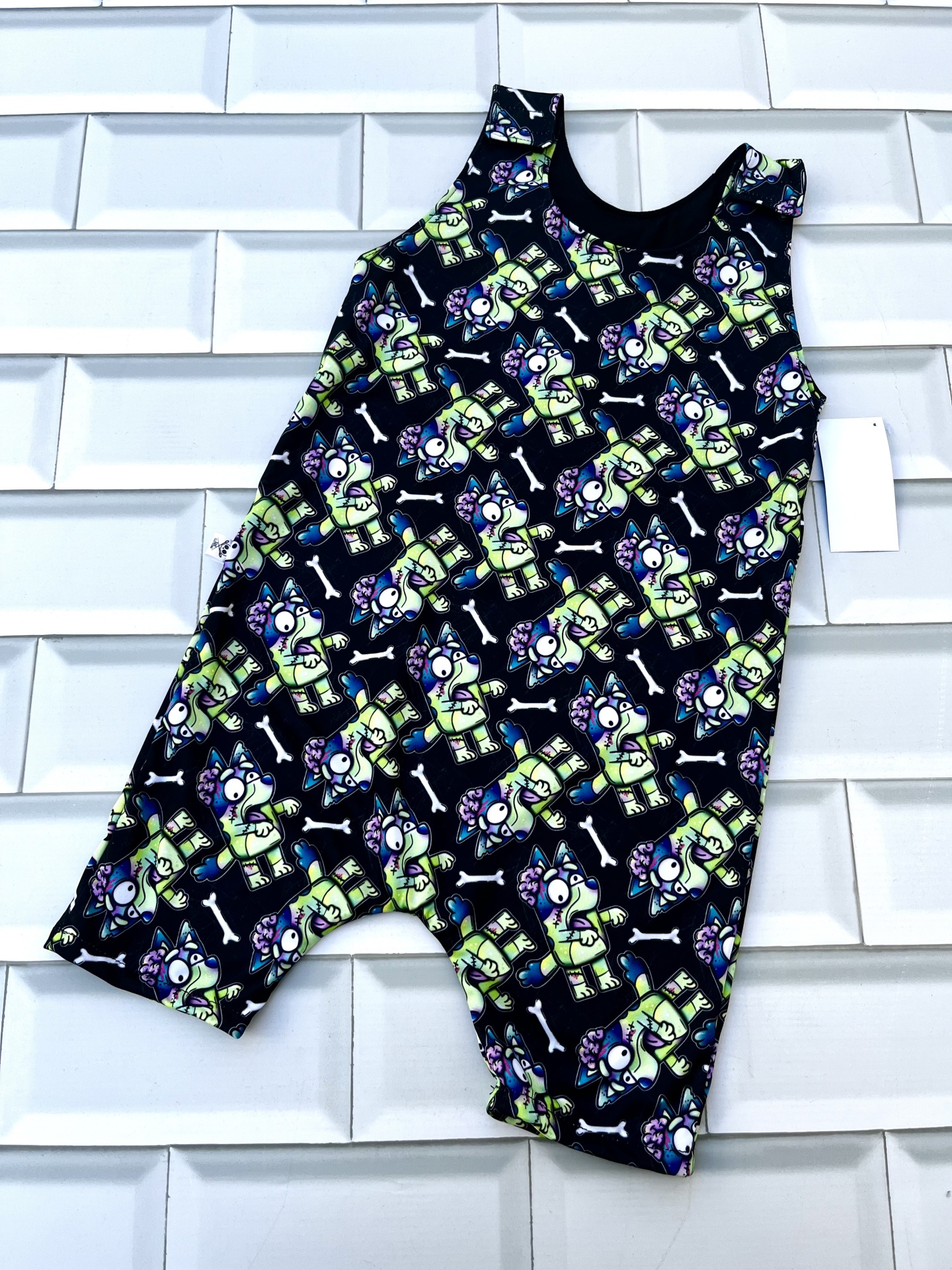 Macacão colorido com padrão de cães e ossos sobre fundo preto