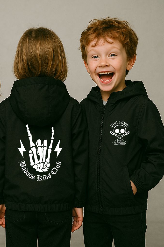 Crianças com casacos pretos com capuz e estampas brancas, uma de frente sorrindo outra de costas