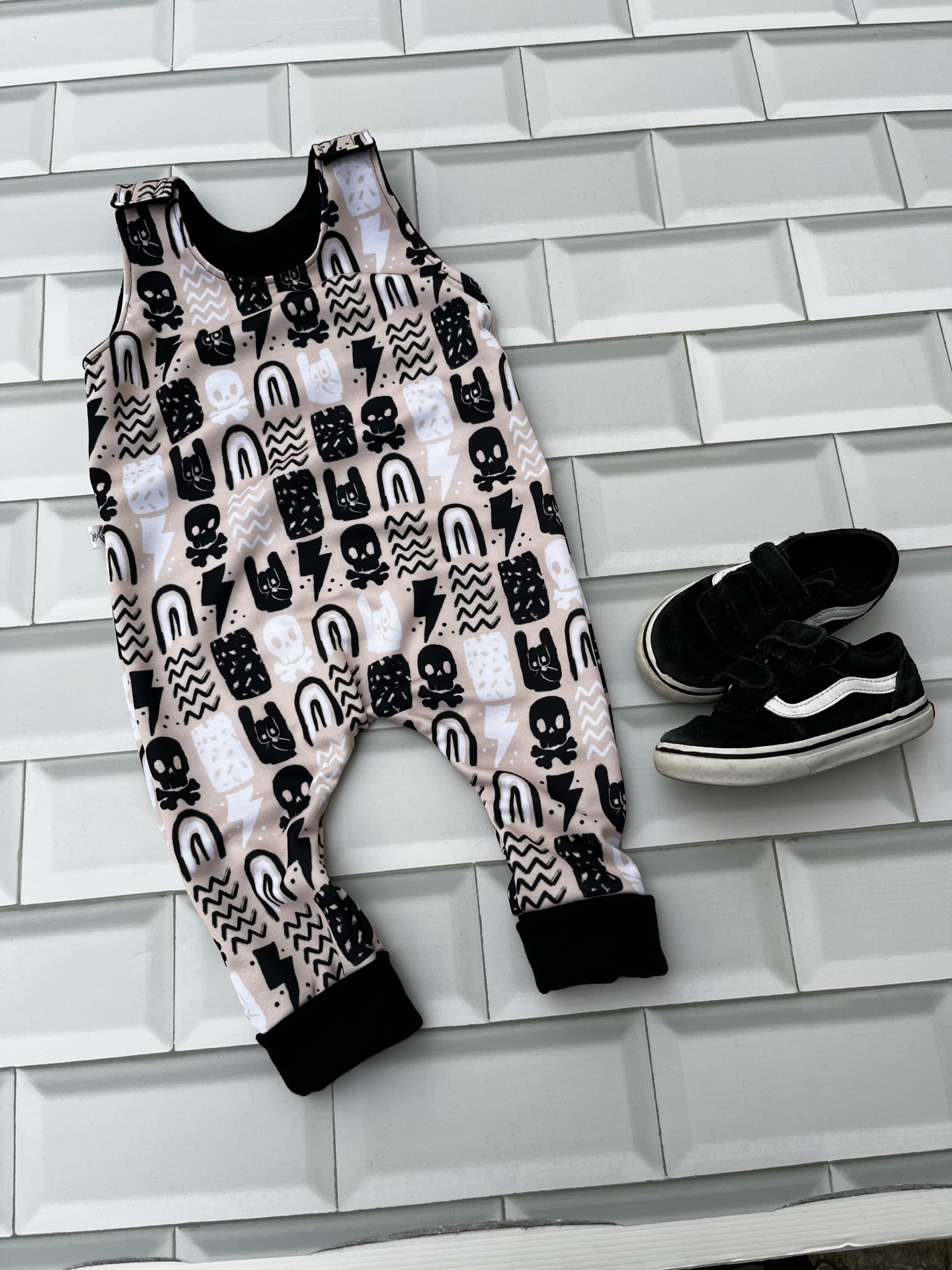 Macacão de bebé estampado e sapatilhas pretas sobre azulejos brancos 3D
