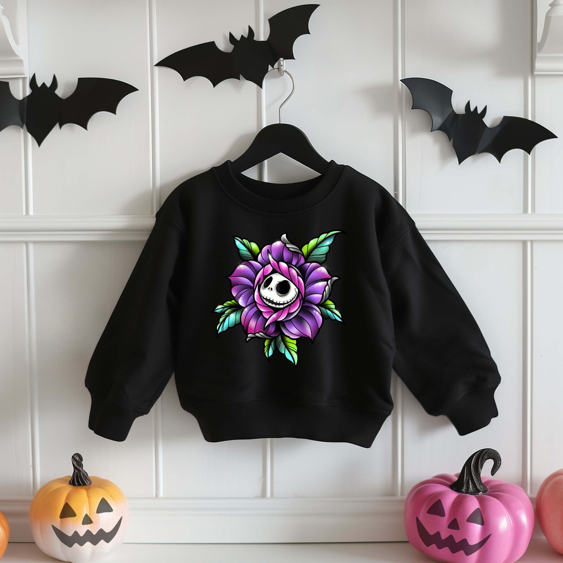 Sweatshirt preta de criança com estampa de flor roxa e rosto de caveira branca ao centro