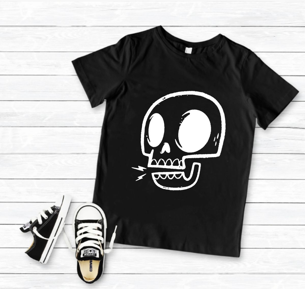 T-shirt preta com estampa de caveira branca e ténis preto e branco em chão de madeira clara