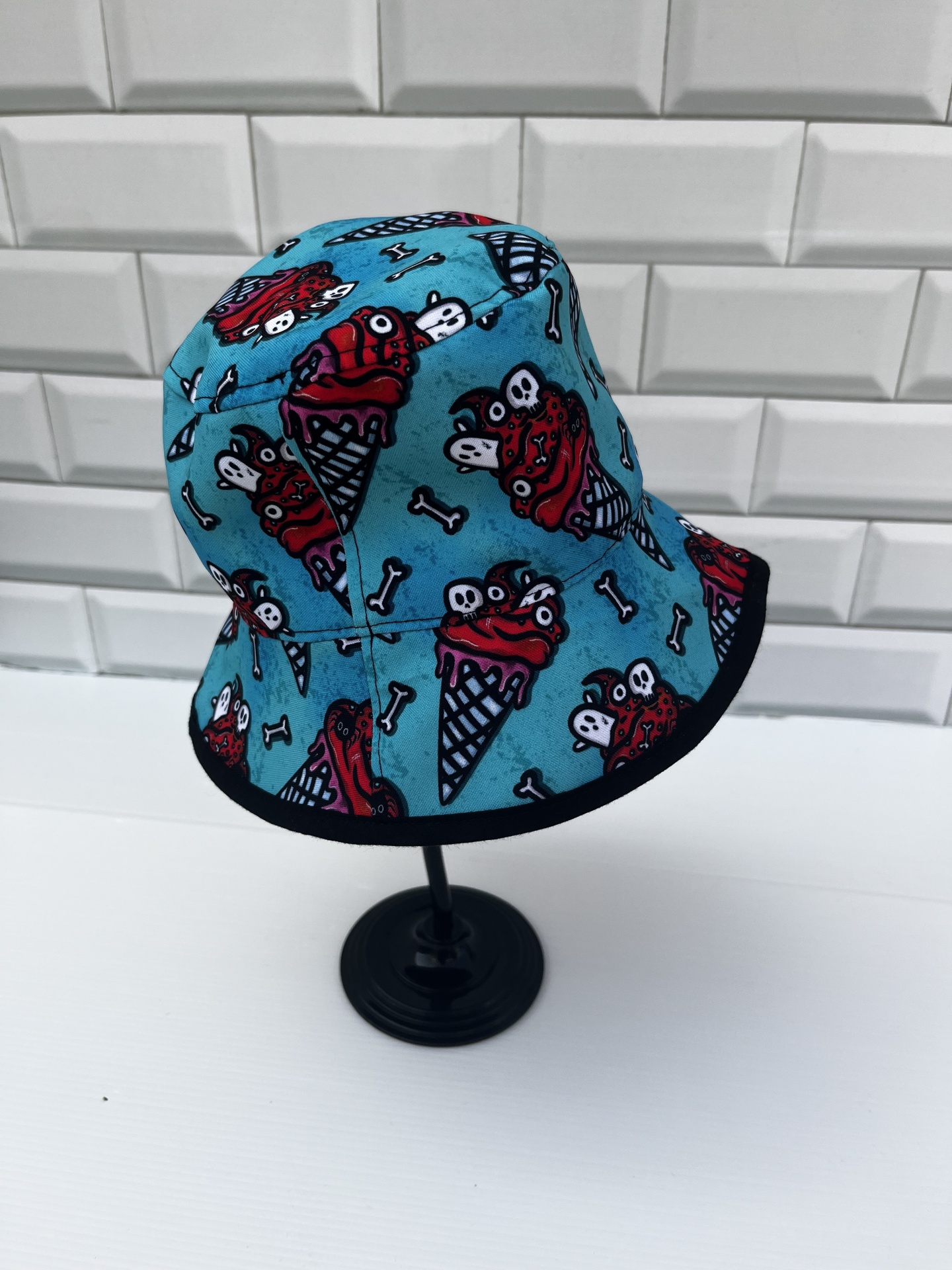 Chapéu pescador azul com padrão de gelados e ossos em suporte preto