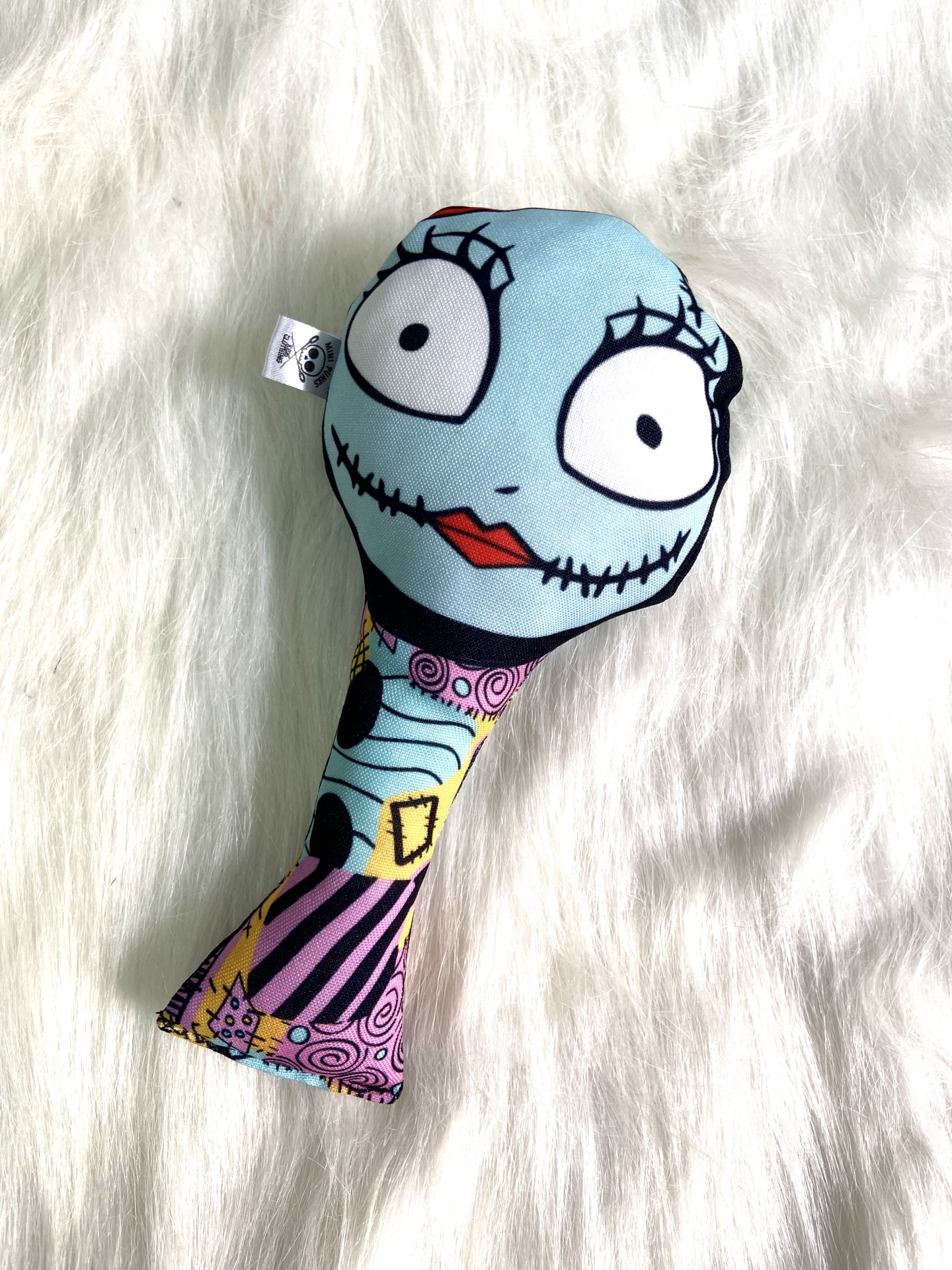 Brinquedo colorido com rosto azul sobre superfície branca peluda